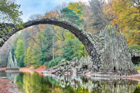 Fabulous autumn landscape in Azalea and Rhododendron Park Kromlau. Rakotz Bridge (Rakotzbrucke,...