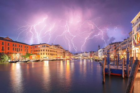 Stunning lightning at night sky over city of f Venice with famous Canal Grande and Rialto Bridge. Popular travell destination. Location: Venice, Veneto region, Italy, Europeの写真素材