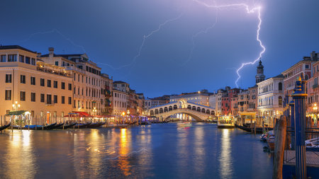 Stunning lightning at night sky over city of f Venice with famous Canal Grande and Rialto Bridge. Popular travell destination. Location: Venice, Veneto region, Italy, Europeの写真素材