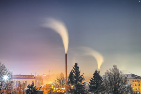 View of working heat station with steam from the pipe at night over the city. Winter landscapeの写真素材
