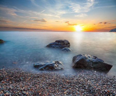 Amazing seascape during sunset. Beautiful natural seascape at long exposure. Stones at foregroundの写真素材