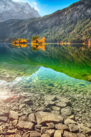 Stunning autumn landscape of Eibsee Lake in front of Zugspitze summit under sunlight. Location:...