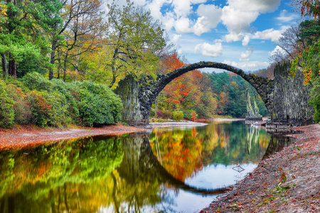 Breathtaking autumn landscape in Kromlau Rhododendron Park. Rakotz Bridge (Rakotzbrucke)  Location:...