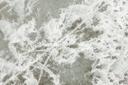 Surface of thick ice layer on lake, weathered by numerous thaw and freeze cycles.の写真素材
