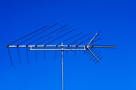 Old rooftop directional tv antenna on blue sky.の写真素材