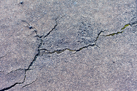 Cracks in asphalt pavement of walkway.