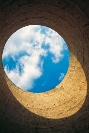 Looking up from the interior of a cooling tower/ chimney showing a blue-white circle of sky resembling our blue planet earth in space.の写真素材