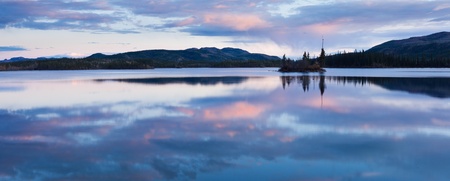 Calm lake reflecting sky at sunset, Twin Lakes, Yukon Territory, Canada.の写真素材