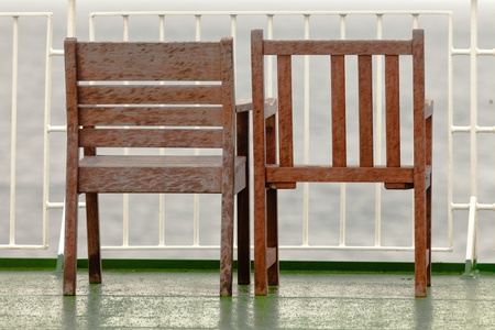 Two old wooden chairs standing abandoned on balcony next to each otherの写真素材