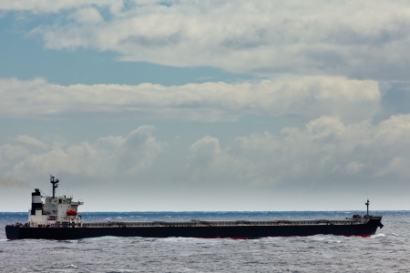 Loaded oil tanker, long and low in the water, on the ocean sea under stormy sky cloudsの写真素材