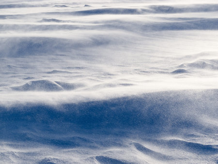 Blizzard background texture pattern  drifting snow crystals driven by strong wind creating snow surface refiefの写真素材