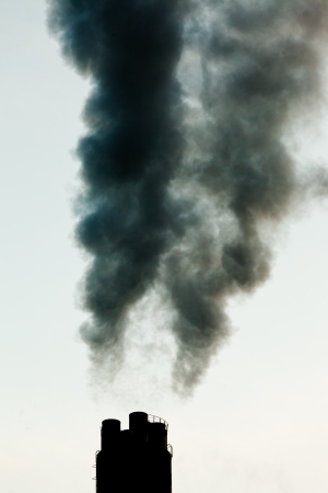 Smokestack chimneys belching black smoke  pollutants and greenhouse gas into the atmosphere polluting and contributing to global warmingの写真素材