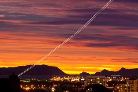Sunset and light trail of starting airplane over Manukau  southern suburb of Auckland  New Zealandの写真素材