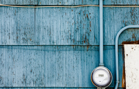 Modern smart grid residential digital power supply meter mounted on grungy blue exterior wooden wallの写真素材