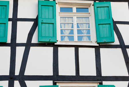 Shuttered window in an ancient timber frame house in Germany with pretty green shutters and lace curtains  exterior architectural backgroundのeditorial素材