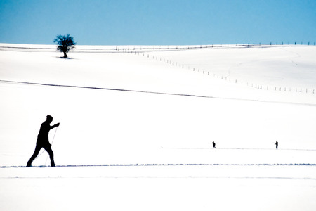Active cross country skier following an x-country ski track across a flat expanse of winter snow exercising winter sportsの写真素材