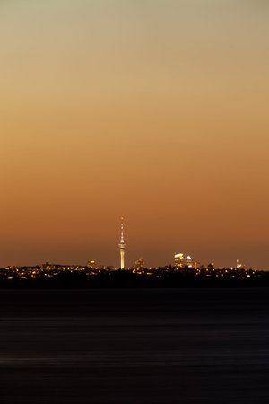 Distant skyline of Auckland City, New Zealand, with Sky Tower illuminated in twilight dusk after sunsetの写真素材