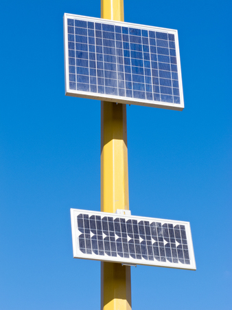 Solar electric panels mounted on yellow pole providing off-grid power in full sun against blue skyの写真素材