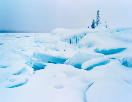 Frozen lake shore winter landscape of jumbled ice floes and white snow cover on grey midwinter day