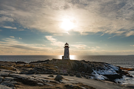 Famous tourist destination Peggy's Cove Lighthouse on granite rock cliffs overlooking calm Atlantic...