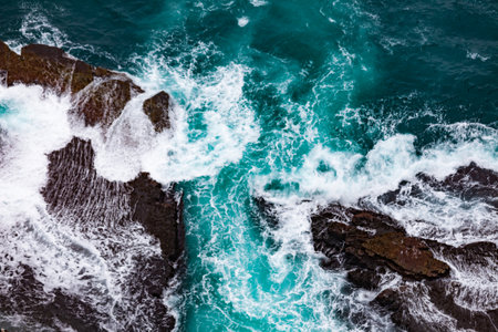 Aerial view seascape of big dynamic surf waves crashing turbulent onto rocky shore nature abstract background patternの写真素材