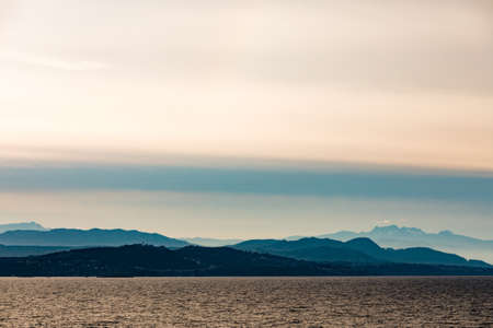 Distant eastern shore of Vancouver Island silhouette of forested hills and mountains veiled by haze, Pacific Ocean Coast of British Columbia, BC, Canadaの写真素材