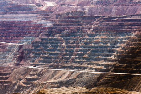 Colorful layered bedrock terraces with haul road of deep open-pit copper mine industrial mining...