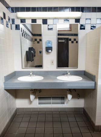 Indoor architecture of public washroom sinks and mirrors in tiled corner nicheの写真素材