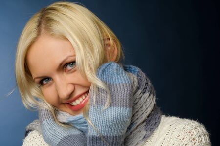 Beatiful blonde girl in winter clothes.She is dressed in sweater, scarf and mittens.の写真素材