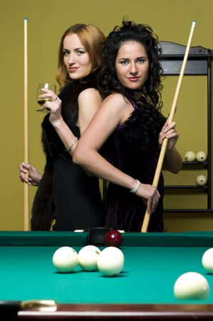 Two beautiful girls are playing billiards and drinking cognacの写真素材
