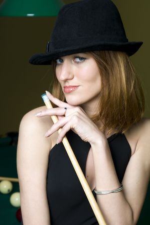 Portrait of the beautiful woman in black dress and hat with cueの写真素材