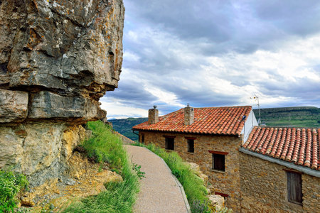 Sunset mountain landscape with big overhung rock. Small old town Ares, Spain.