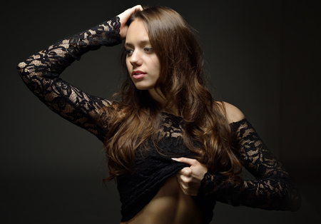 Torso portrait of the beautiful woman with long brown hair in lace lingerie. Studio with dark background.の写真素材