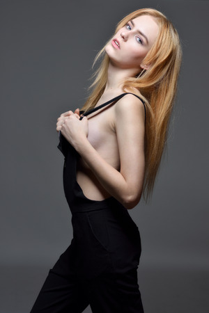 Portrait of the sexy beautiful woman with long red hair in black clothes posing in studio with grey background.の写真素材