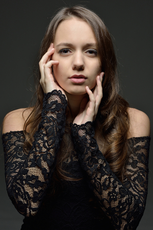 Torso portrait of the beautiful woman with long brown hair in lace lingerie. Studio with dark background.の写真素材