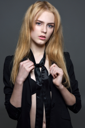 Portrait of the sexy beautiful woman with long red hair in black clothes posing in studio with grey background.の写真素材