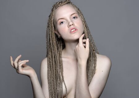 portrait of the beautiful blonde young  woman with pigtails and natural make up posing with her armsの写真素材