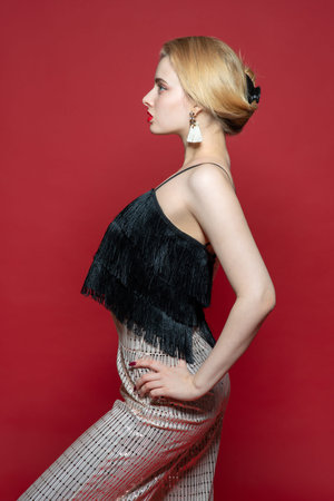 Beautiful sexy woman in black top. Profile portrait in studio with red background.