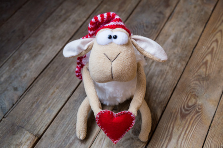 sheep with red heart on wooden backgroundの写真素材