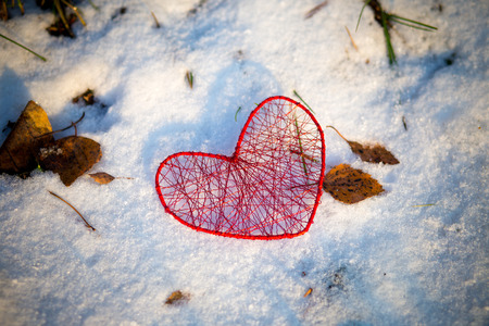red heart handmade of a metal wire on snowy groundの写真素材