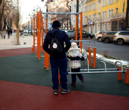 Man and child are walking in the park, near the merry-go-round
