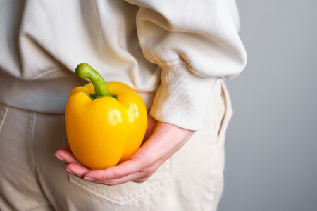 Colored bell pepper in girl hands. Ripe fresh big sweet pepper. Healthy food, organic vegetables. Natural vitamins, raw ingredient for eating. Handpicked bio capsicumの写真素材
