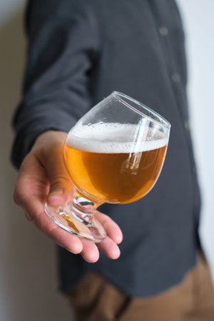 A glass of beer in the hands of a man. Tasting brewed craft beer. Lager beer with beautiful foam....
