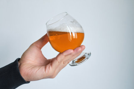 A glass of beer in the hands of a man. Tasting brewed craft beer. Lager beer with beautiful foam. Cold refreshment beverage. Alcohol drink from pub. Relaxation and enjoymentの写真素材