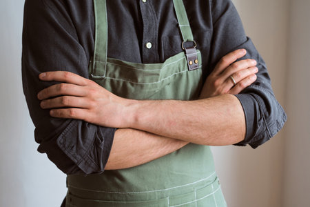 A man in a kitchen apron. Chef work in the cuisine. Cook in uniform, protection apparel. Job in food service. Professional culinary. Green fabric apron, casual stylish clothingの写真素材