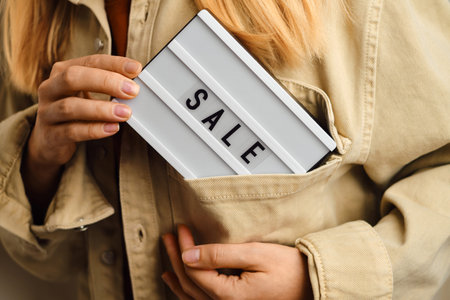 Light box with text SALE in the hands of a girl. Season sale, holiday shopping. Special offer for...