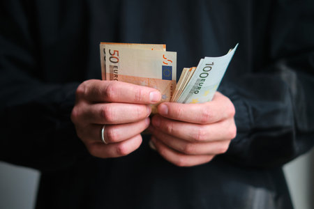 Man holds money in his hands. Cash in Euro for payment or exchange. Male counts salary in euro banknotes. Saving money, withdrawal banking deposit. European money. Financial crisisの写真素材