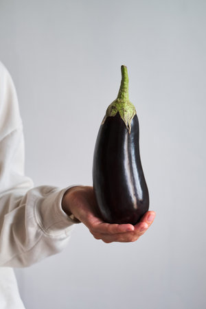 Fresh ripe eggplant in woman hands. Raw big purple aubergine. Healthy food, organic vegetables. Violet squash close-up. Natural vitamins, raw ingredient for eatingの写真素材