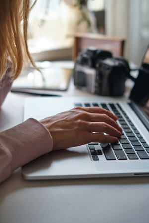Woman working on laptop in home. Freelance photographer edit photos on computer. Professional photography business. Girl workspace with computer and photo camera. Creative artistの写真素材