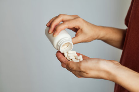 Woman pours pills or vitamins from a jar onto her hand. Taking vitamins or medications. The concept...